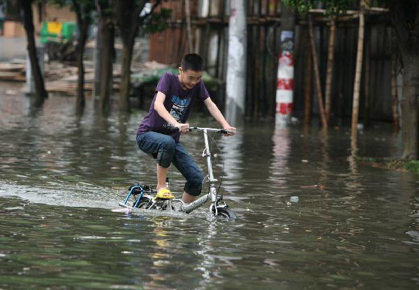 A young man rides on a flooded street in Quanzhou City, southeast China&apos;s Fujian Province, May 23, 2010. Heavy rain hit the province on May 22 and 23. [Xinhua] 