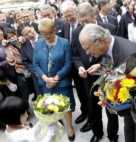 Swedish King Carl XVI Gustaf (R, front) receives flowers during his vitit to the Sweden Pavilion at the World Expo park in Shanghai, east China, May 23, 2010, the National Pavilion Day for Sweden. (Xinhua/Liu Ying) 