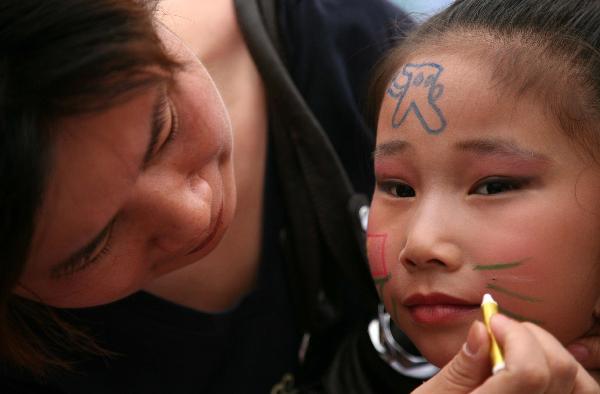 A mother draws colored patterns on her daughter's face in Nanjing, capital of east China's Jiangsu Province, May 29, 2010.