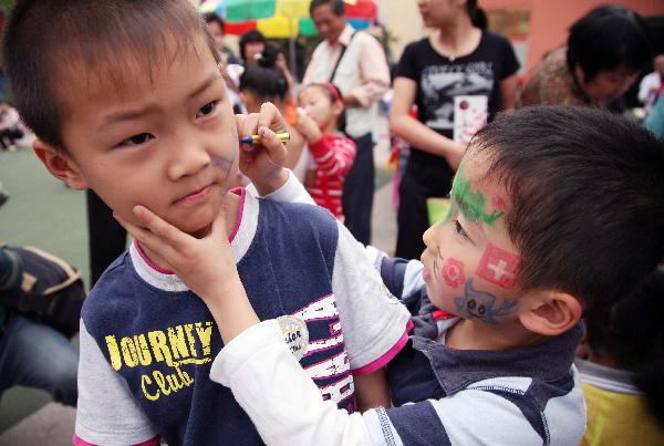 A boy draws colored patterns on his friend's face in Nanjing, capital of east China's Jiangsu Province, May 29, 2010.