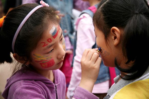 A girl draws colored patterns on her friend's face in Nanjing, capital of east China's Jiangsu Province, May 29, 2010.