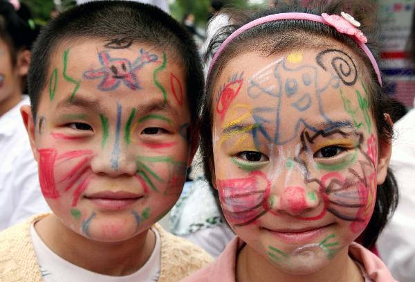 Children show colored patterns drawn on their faces in Nanjing, capital of east China's Jiangsu Province, May 29, 2010. 