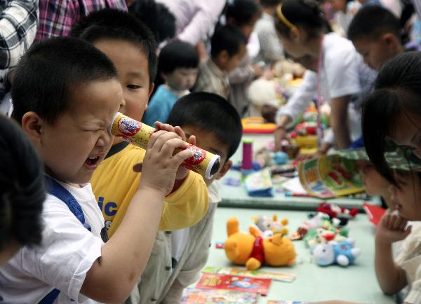 A boy looks into a kaleidoscope at a barter fair held in a kindergarten in Wuxi City, east China's Jiangsu Province, May 29, 2010. 