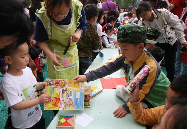 Children exchange their articles at a barter fair held in a kindergarten in Wuxi City, east China's Jiangsu Province, May 29, 2010. As the International Children's Day draws near, a total of 460 children took part in the barter fair with their parents on Saturday. By exchanging the used toys and books, children learnt more about low-carbon life style.