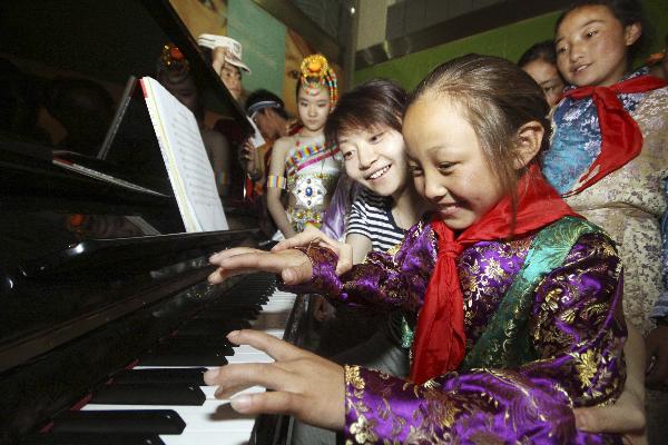 A girl from northwest China&apos;s quake-hit Yushu Prefecture plays piano at the youth activity center of Tianjin, north China, May 30, 2010. 