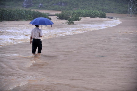 A man wades through flood waters in Laibin City, south China's Guangxi Zhuang Autonomous Region, June 1, 2010.