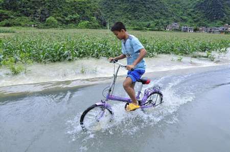 A boy rides bicycle on a flooded street in Du'an, south China's Guangxi Zhuang Autonomous Region, June 1, 2010.