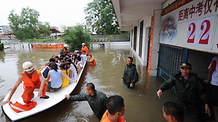 Firefighters help evacuate students who are trapped by flood at a school in Laibin City, south China's Guangxi Zhuang Autonomous Region, June 1, 2010. It is said 11 townships in Guangxi have received more than 300 millimeters of rain since Monday night, with several suffering from flooding.