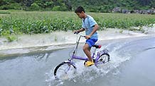 A boy rides bicycle on a flooded street in Du'an, south China's Guangxi Zhuang Autonomous Region, June 1, 2010.