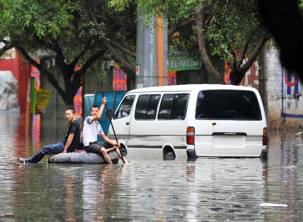 Local residents ride on a self-made boat on a flooded street in Laibin City, southwest China's Guangxi Zhuang Autonomous Region, June 2, 2010.