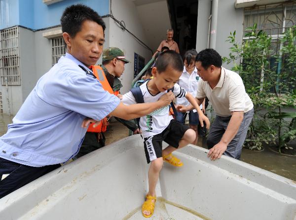 A policeman helps a boy to get on a lifeboat on a flooded street in Laibin City, southwest China's Guangxi Zhuang Autonomous Region, June 2, 2010. 