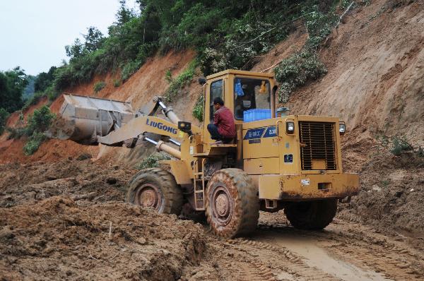 Rescuers clean the road hit by landslides in Rongxian County of Yulin City, south China's Guangxi Zhuang Autonomous Region, June 2, 2010. 