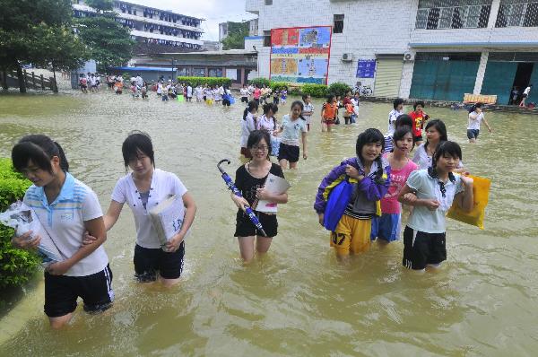 Students of grade 3 walk in the flood at the Second Senior High School in Yao Ethnic Autonomous County of Du'an in south China's Guangxi Zhuang Autonomous Region, June 2, 2010.