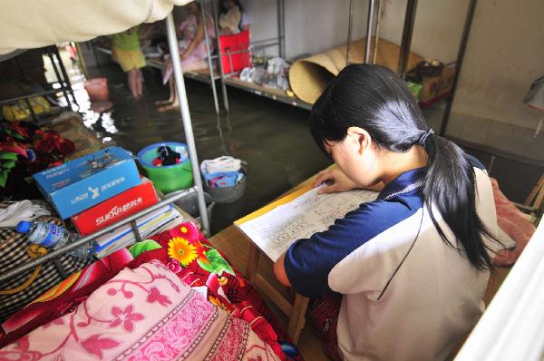 A student of grade 3 studies at the flooded dormitory at the Second Senior High School in Yao Ethnic Autonomous County of Du'an in south China's Guangxi Zhuang Autonomous Region, June 2, 2010. 