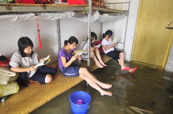 Students of grade 3 study at the flooded dormitory at the Second Senior High School in Yao Ethnic Autonomous County of Du'an in south China's Guangxi Zhuang Autonomous Region, June 2, 2010. 