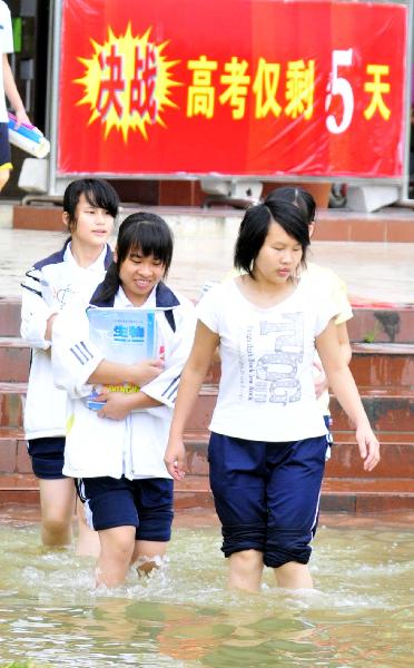 Students of grade 3 walk in the flood at the Second Senior High School in Yao Ethnic Autonomous County of Du'an in south China's Guangxi Zhuang Autonomous Region, June 2, 2010.