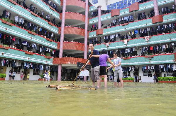 Wang Mingwu, a grade 3 teacher, transfers students by a raft at the flooded Second Senior High School in Yao Ethnic Autonomous County of Du'an in south China's Guangxi Zhuang Autonomous Region, June 2, 2010. 