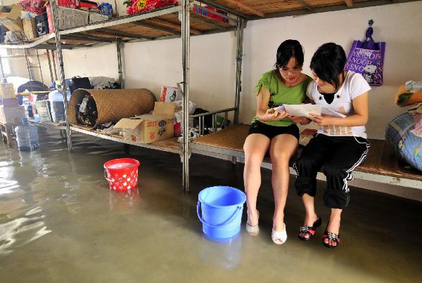 Two students of grade 3 study at the flooded dormitory at the Second Senior High School in Yao Ethnic Autonomous County of Du'an in south China's Guangxi Zhuang Autonomous Region, June 2, 2010.