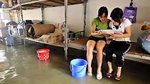 Two students of grade 3 study at the flooded dormitory at the Second Senior High School in Yao Ethnic Autonomous County of Du'an in south China's Guangxi Zhuang Autonomous Region, June 2, 2010.