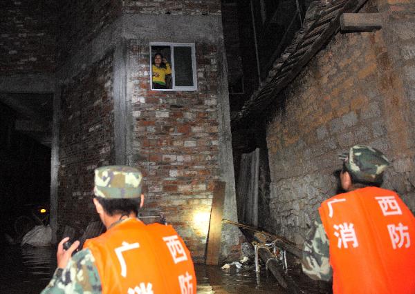 Fire fighters are ready to rescue a trapped woman in a house in Laibin, southwest China's Guangxi Zhuang Autonomous Region, on June 2, 2010.