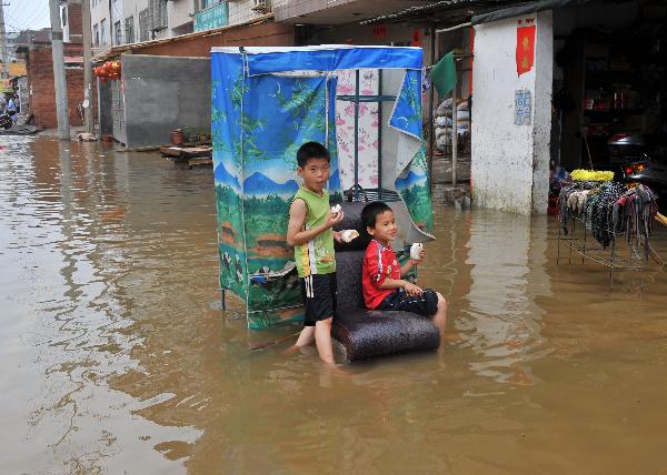 Local children eat food in floods in Laibin, southwest China's Guangxi Zhuang Autonomous Region, on June 3, 2010. 