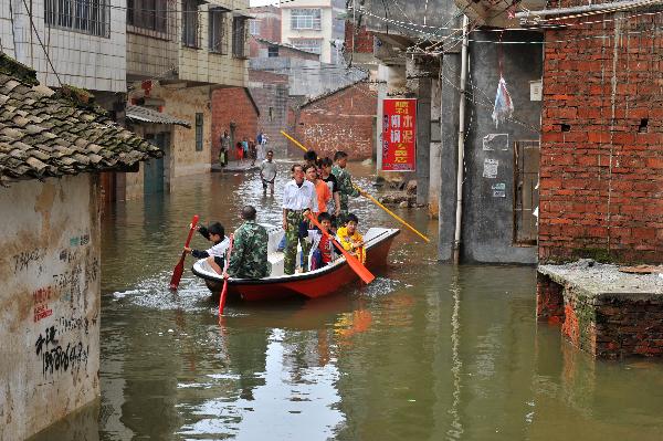 Local officials and residents transport trapped people on a boat in Laibin, southwest China's Guangxi Zhuang Autonomous Region, on June 3, 2010.