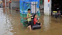 Local children eat food in floods in Laibin, southwest China's Guangxi Zhuang Autonomous Region, on June 3, 2010.