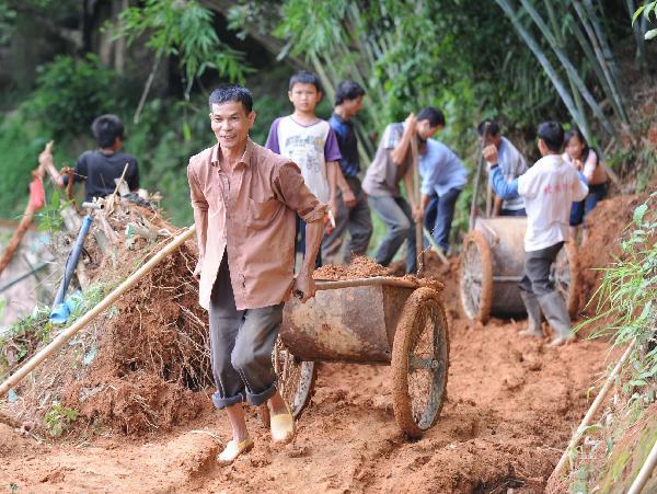 Villagers take part in repairing the road destroyed by flood in Dahe Village of Cencxi, south China's Guangxi Zhuang Autonomous Region, June 3, 2010. 