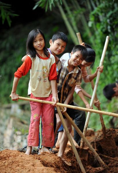 Children take part in repairing the road destroied by foold in Dahe Village of Cencxi, south China's Guangxi Zhuang Autonomous Region, June 3, 2010. 