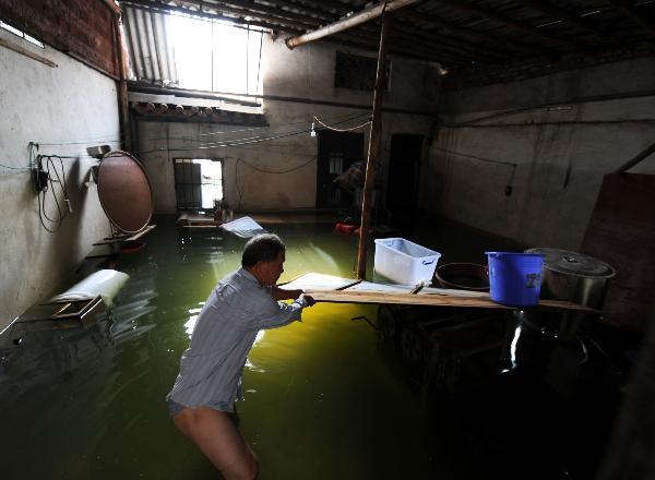 A local resident search for goods in a flooded house at Lingwo, Dongshe district, Laibin city, south China&apos;s Guangxi Zhuang Autonomous Region, June 4, 2010. Some 1,700 residents in Lingwo were still trapped by the flood triggered by heavy rain since Wednesday in Guangxi.