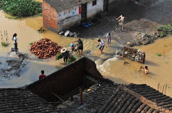 Local residents walk along a flooded street at Lingwo, Dongshe district, Laibin city, south China&apos;s Guangxi Zhuang Autonomous Region, June 4, 2010. Some 1,700 residents in Lingwo were still trapped by the flood triggered by heavy rain since Wednesday in Guangxi.