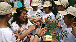 Students from Beijing's 2nd deaf and mute school introduce their paper-made tree model. [CnDG by Jiao Meng]