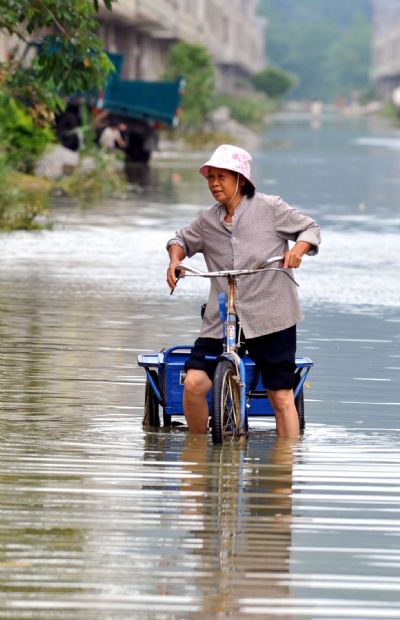 A resident rides a tricycle on a flooded road in Chengjiang Town of Yao Autonomous County of Du&apos;an, southwest China&apos;s Guangxi Zhuang Autonomous Region, June 7, 2010. 