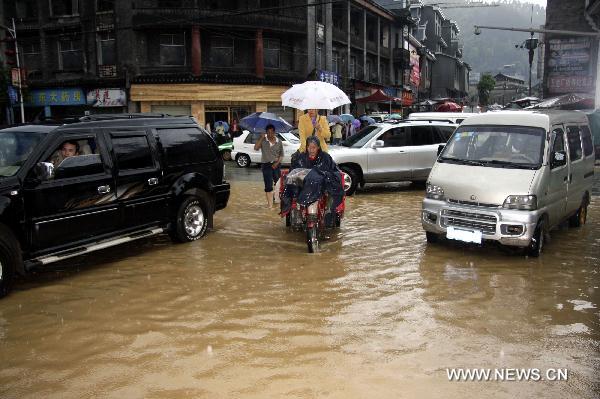 Vehicles and pedestrians wade through the inundated street as torrential water flow of the Tuojiang River surges up after persistent strong rainstorm, at Fenghuang County, central China&apos;s Hunan Province, June 8, 2010. 