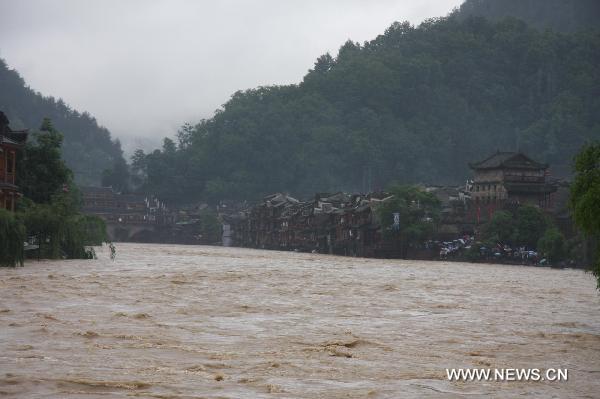 Torrential water flow of the Tuojiang River surges up and inundates part of the streets, at Fenghuang County, central China's Hunan Province, June 8, 2010. 