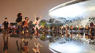Tourists pose for pictures in front of the culture center of the 2010 Shanghai World Expo, in Shanghai, east China, June 11, 2010.