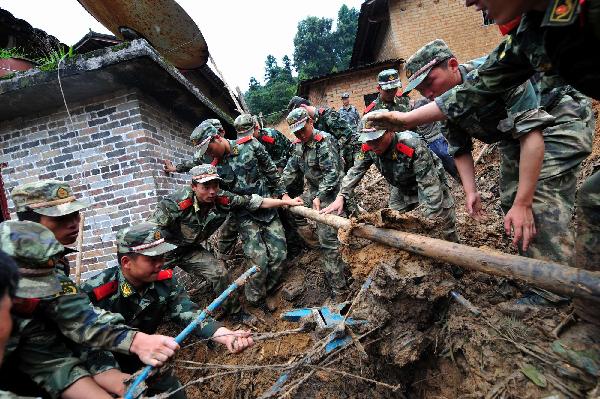 Armed police search for the missing at the site of rainstorm-triggered landslide in Cangwu County of southwest China&apos;s Guangxi Zhuang Autonomous Region, June 16, 2010.