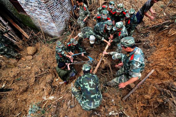 Armed police search for the missing at the site of rainstorm-triggered landslide in Cangwu County of southwest China&apos;s Guangxi Zhuang Autonomous Region, June 16, 2010.