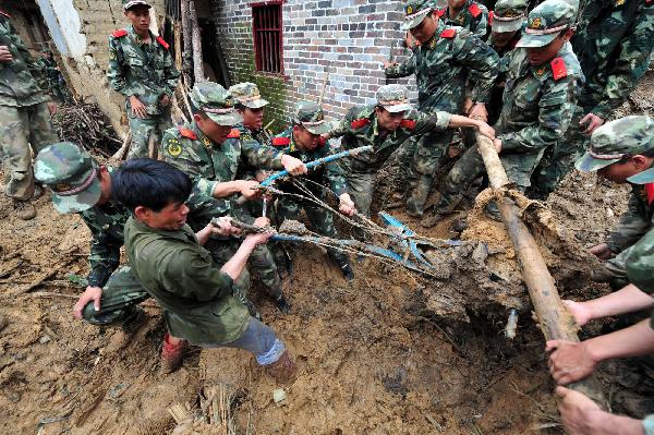 Armed police search for the missing at the site of rainstorm-triggered landslide in Cangwu County of southwest China&apos;s Guangxi Zhuang Autonomous Region, June 16, 2010.