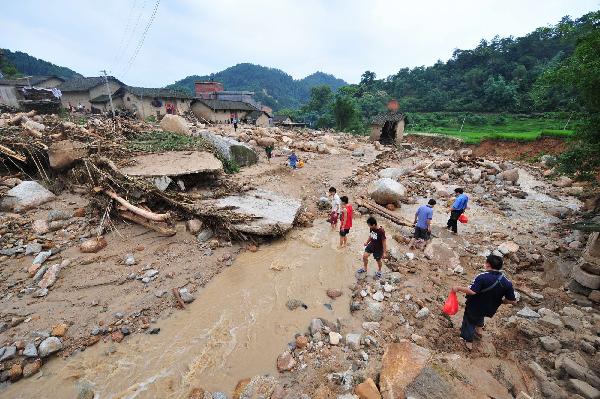 People walk past the debris after floods in Cangwu County of southwest China&apos;s Guangxi Zhuang Autonomous Region, June 16, 2010.