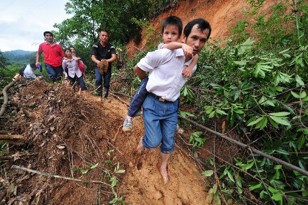 Local residents walk on the road covered with mud and rock after flood in Cangwu County of southwest China&apos;s Guangxi Zhuang Autonomous Region, June 16, 2010. 