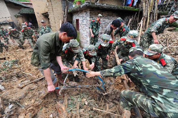 Armed police search for the missing at the site of rainstorm-triggered landslide in Cangwu County of southwest China&apos;s Guangxi Zhuang Autonomous Region, June 16, 2010.