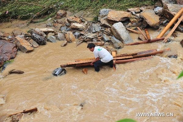 A man tries to take back wood pieces in flood in Cangwu County of southwest China&apos;s Guangxi Zhuang Autonomous Region, June 16, 2010. 