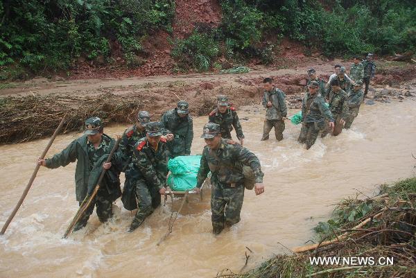 Soldiers carry the bodies of victims out of the Huangshachong tree farm in Hezhou, southwest China's Guangxi Zhuang Autonomous Region, June 16, 2010. The mountain torrent, which occurred in the Huangshachong tree farm Monday night, has left 5 people dead, 5 injured and 3 others missing.