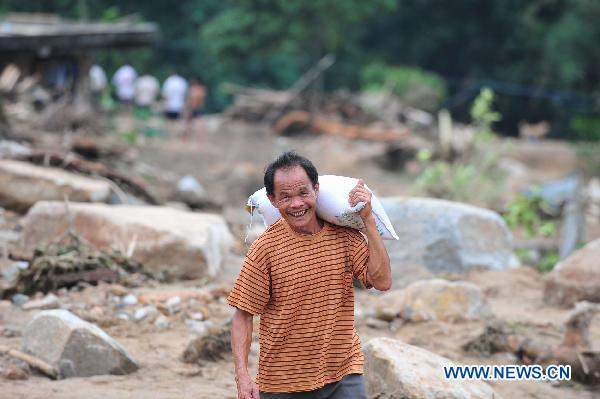 A villager carries relief rice in Shuangshang village of Cangwu, county of southwest China's Guangxi Zhuang Autonomous Region, June 16, 2010. 