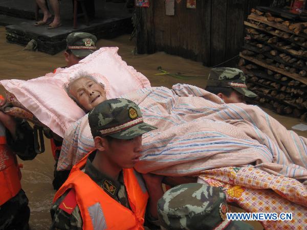 Soldiers transfer an old woman trapped by the flood water at Songxi Town of Qingliu County, southeast China's Fujian Province, June 18, 2010. Five speed boats and 100 armed policemen were dispatched to rescue people who were trapped by the rain-triggered flood in Songxi County. (Xinhua/Lu Lijie)