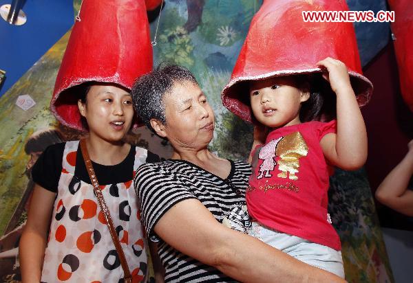 Four-year-old Jiang Yuxiao (R) from Taicang of east China&apos;s Jiangsu Province visits the Germany Pavilion with her parents and grandmother at the World Expo Park in Shanghai, east China, June 20, 2010. 