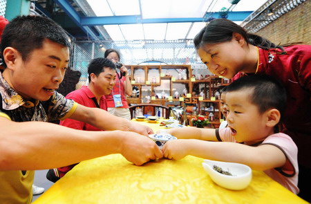 A boy presents a cup of tea to his father on Father's Day at the Shanghai Expo park. 