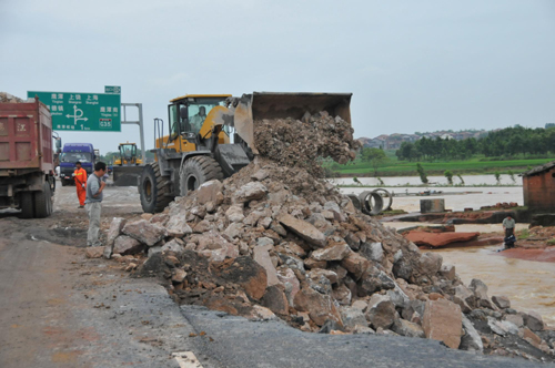 Rescue workers repair the protective net of the ruined Jiangxi section of the Shanghai-Kunming Highway in Yujiang, Jiangxi Province on June 21, 2010.