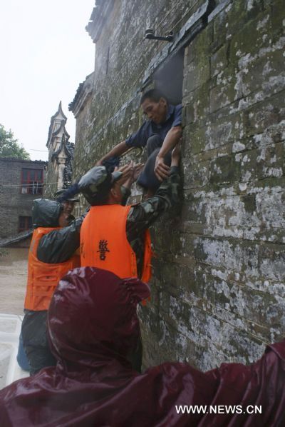 A squad of armed policemen aid a villager out of predicament against heavy rainfall, at Jintan Town, Ji'an City, east China's Jiangxi Province, June 20, 2010. 